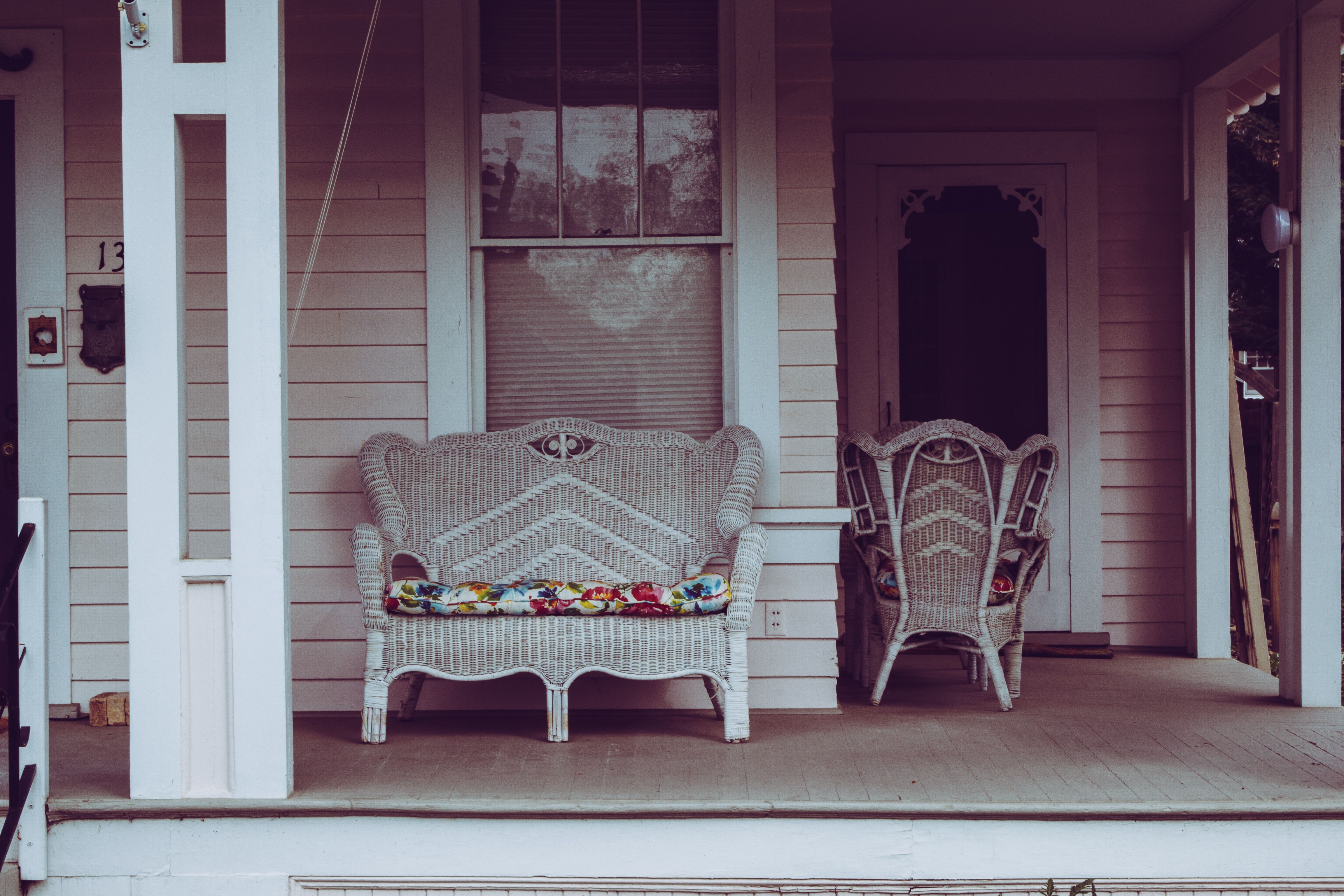 Cozy vintage-style front porch with white wicker chairs and floral cushions