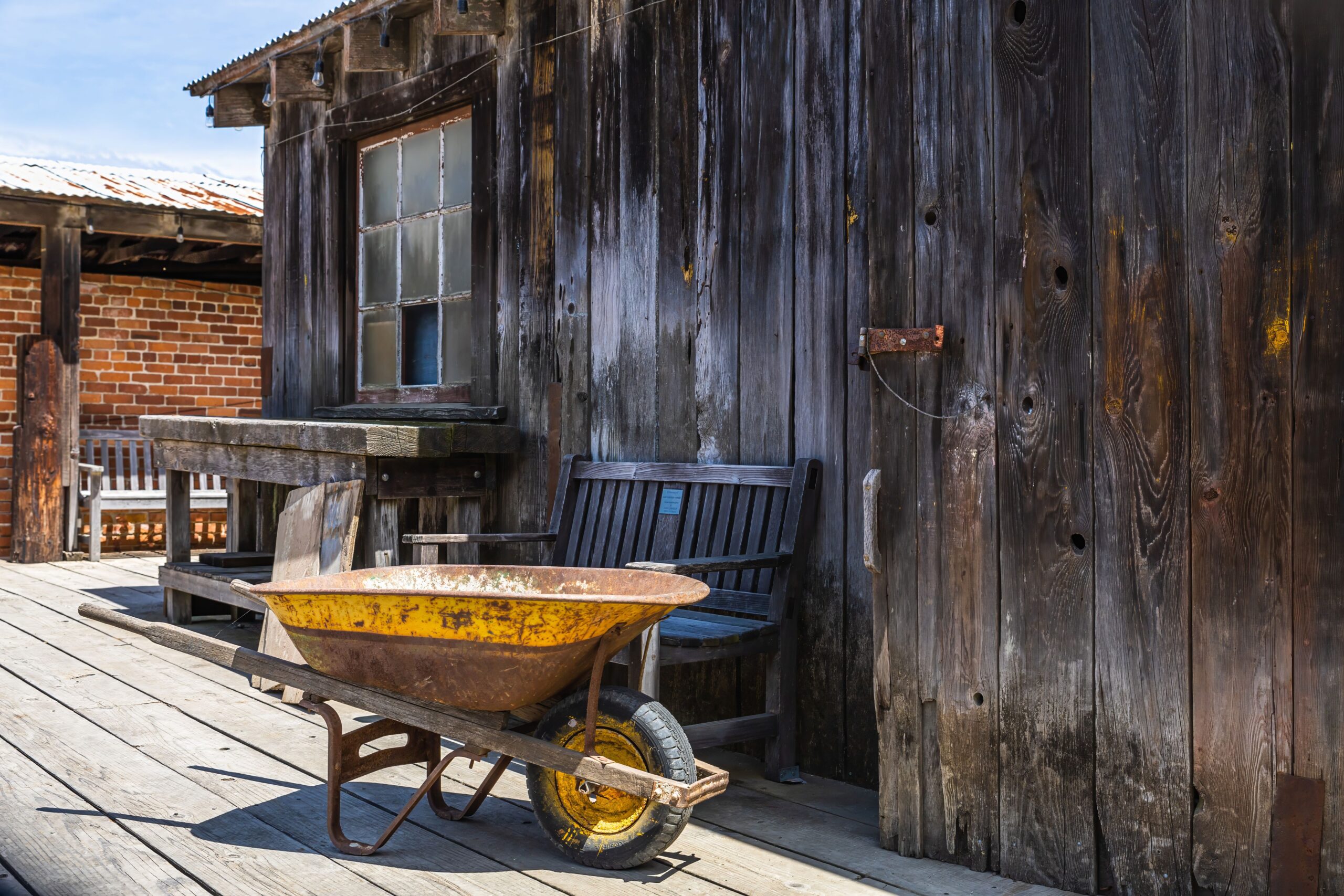 Vintage farmhouse porch with a wooden bench and weathered wheelbarrow
